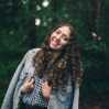 Photo of Devri, woman with dark straight hair standing in front of trees